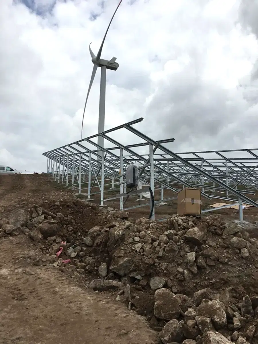 GES konstrüksiyon montajı — arazi üzeri çelik taşıyıcı yapı ve rüzgar türbini